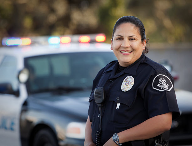 Police officer smiling, shown by her patrol car